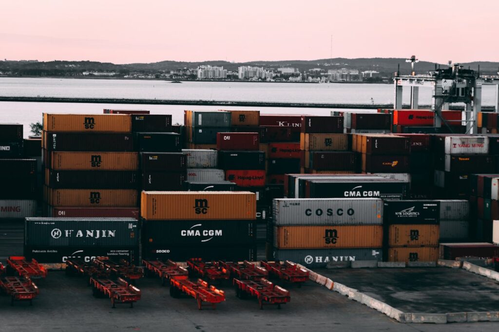 A bustling container yard at a seaport with shipping containers stacked and ready for transport at twilight.